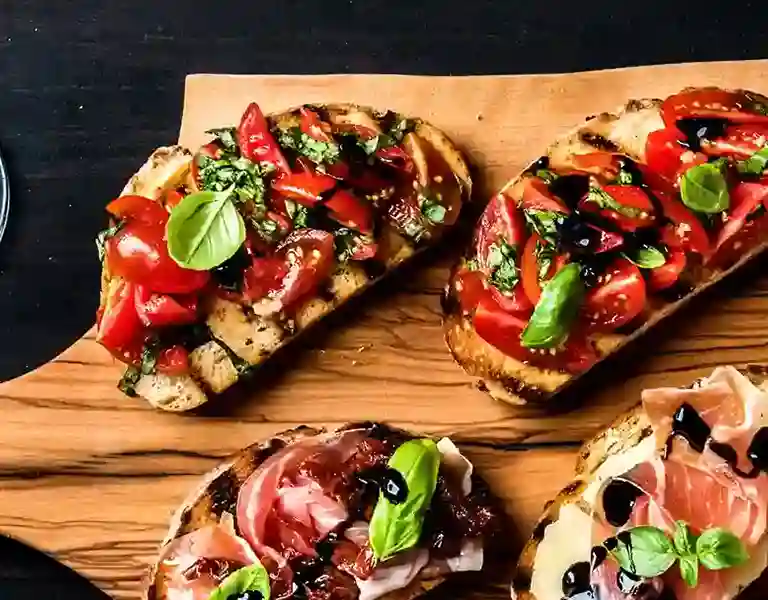A mouthwatering image of bruschetta topped with ripe tomatoes, fresh basil, and drizzled with olive oil, served on a rustic wooden board